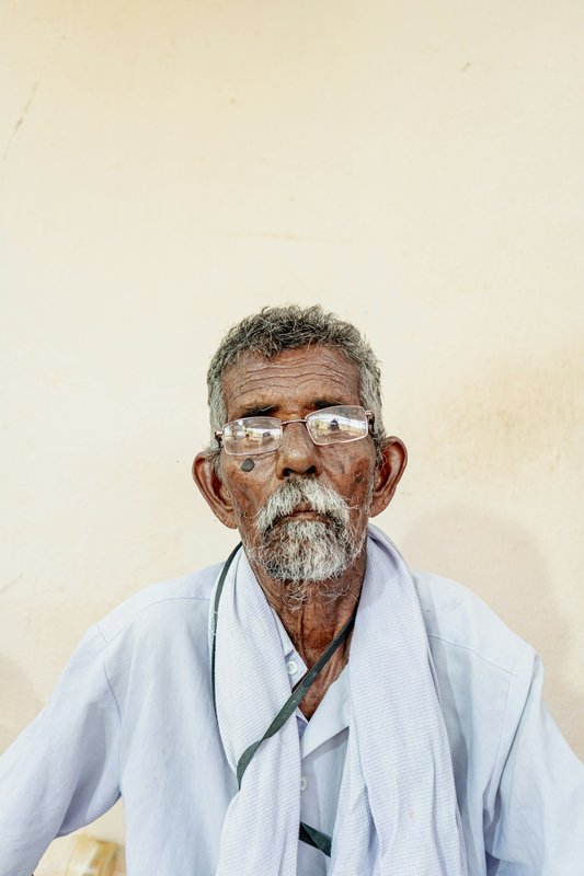 Elderly Indian man reading with clear eyesight wearing glasses outdoors