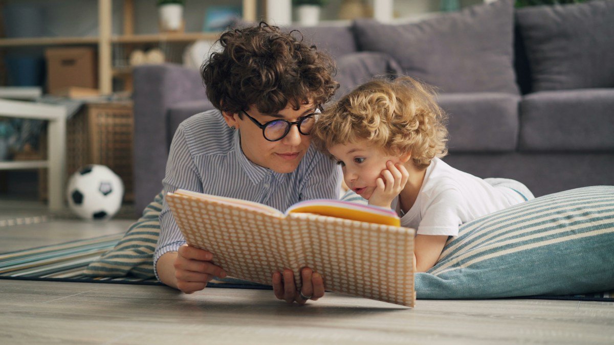 Mother and child reading a picture book together in warm natural light
