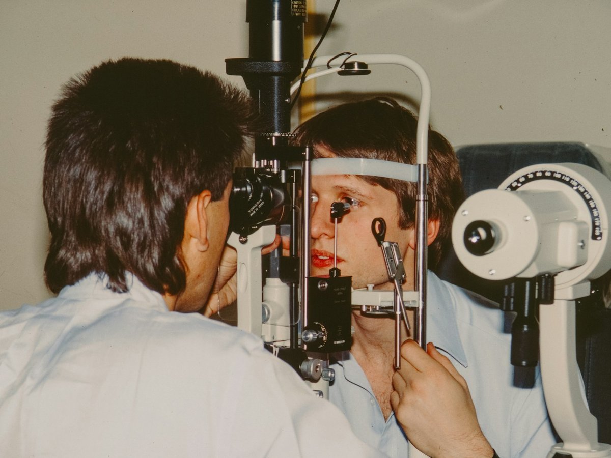 Ophthalmologist examining an adult patient's eyes at the slit lamp biomicroscope in consultation room