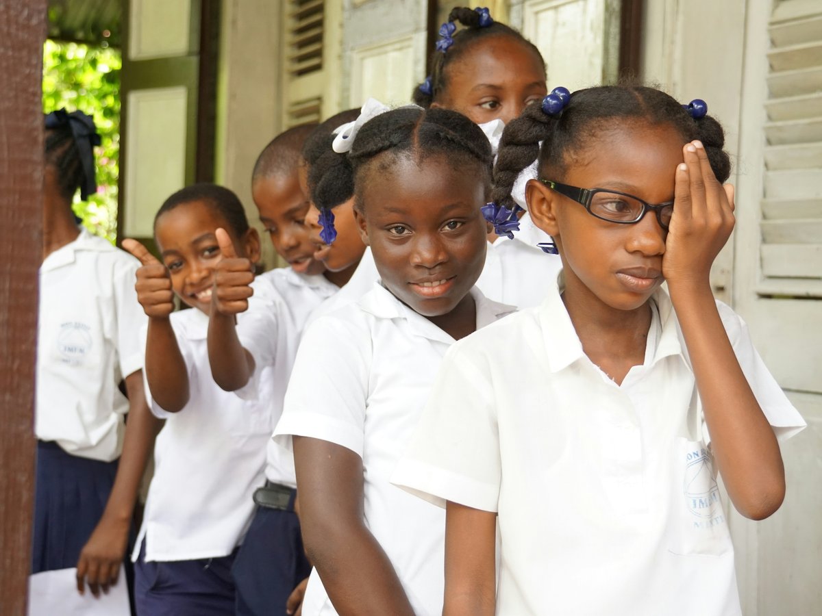 School children in Virudhunagar district lining up for a community vision screening, one child covering an eye during the test