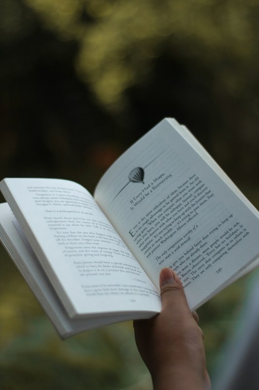 Hands holding an open journal while reading, demonstrating tactile close-up vision