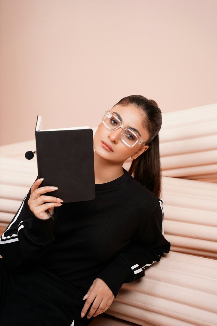 Elderly Indian woman wearing glasses comfortably reading a book with warm ambient lighting