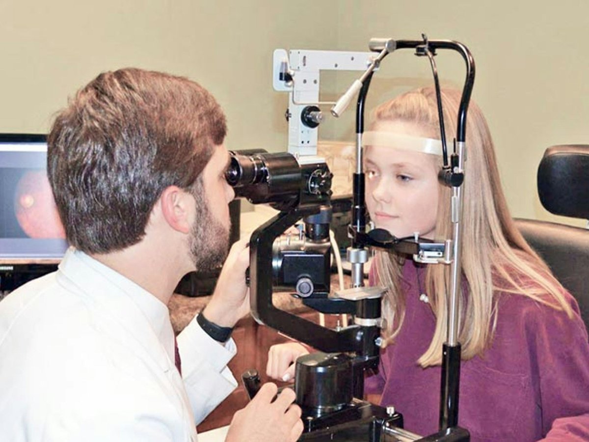 Ophthalmologist examining a patient's eyes at the digital slit lamp during pre-LASIK corneal evaluation with screen display
