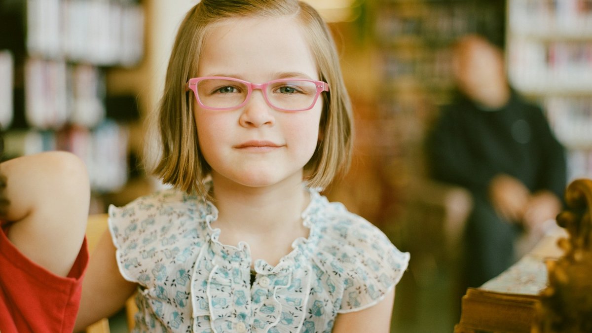 Young girl smiling confidently while wearing comfortable prescription eyeglasses prescribed for vision correction