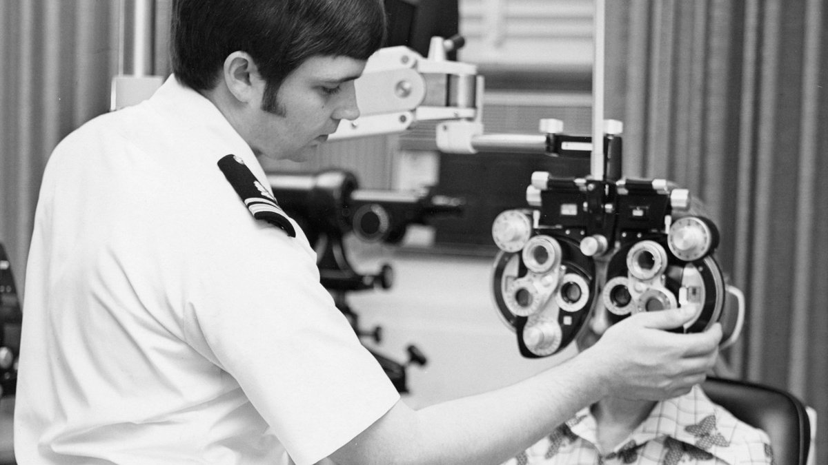 Pediatric eye specialist conducting a careful visual acuity and refraction test using a phoropter